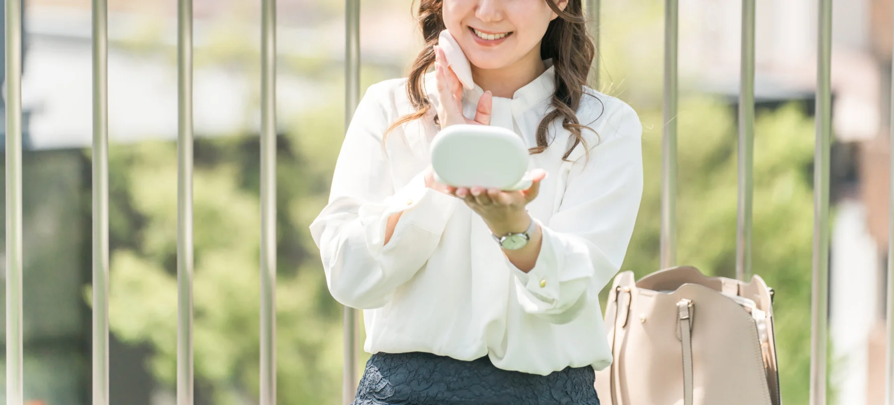 メイクの上からコンパクトパフで丁寧に塗り直しをする女性のイメージ