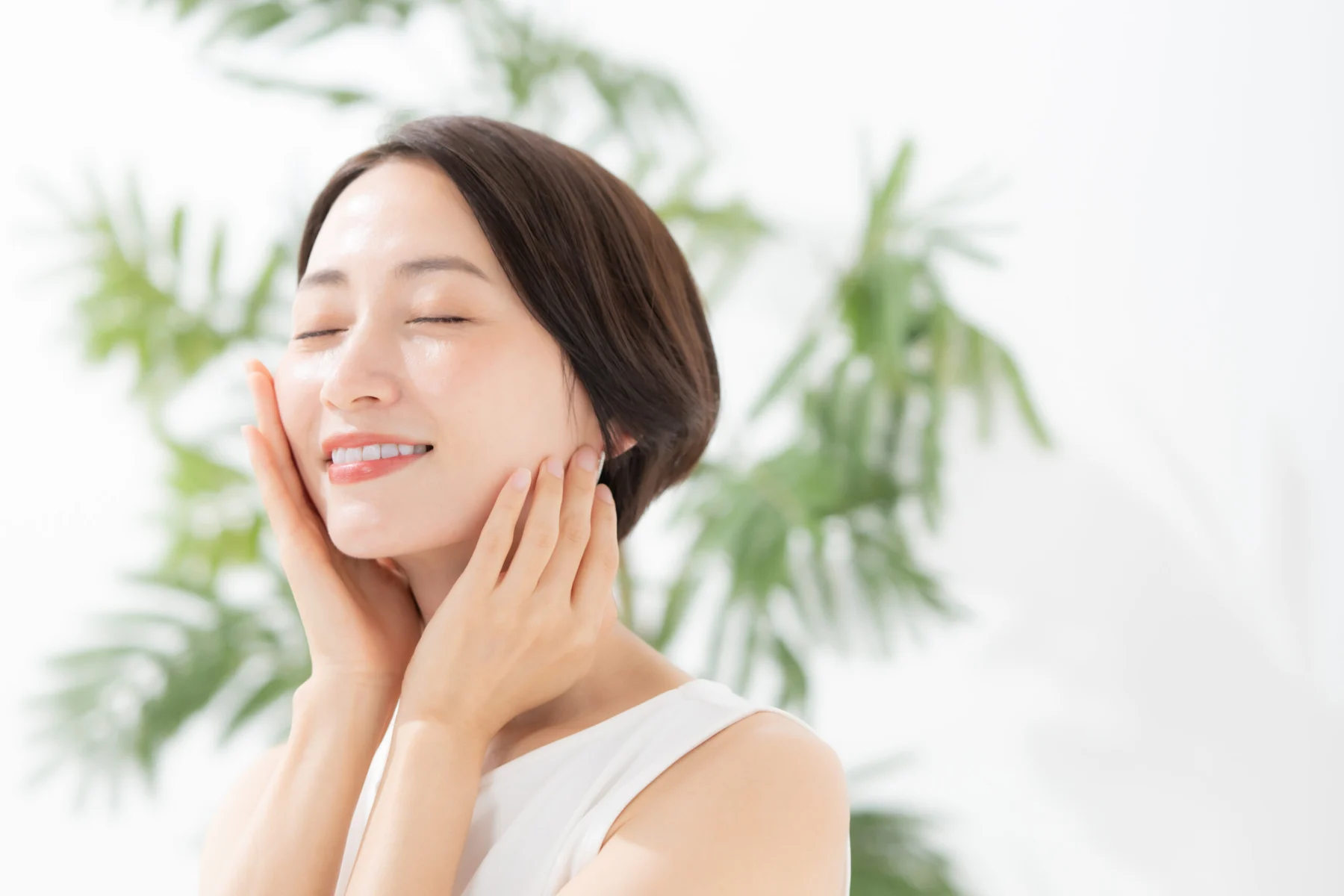 透明感のある空間に整然と並べられた上質なスキンケア容器と植物のイメージ