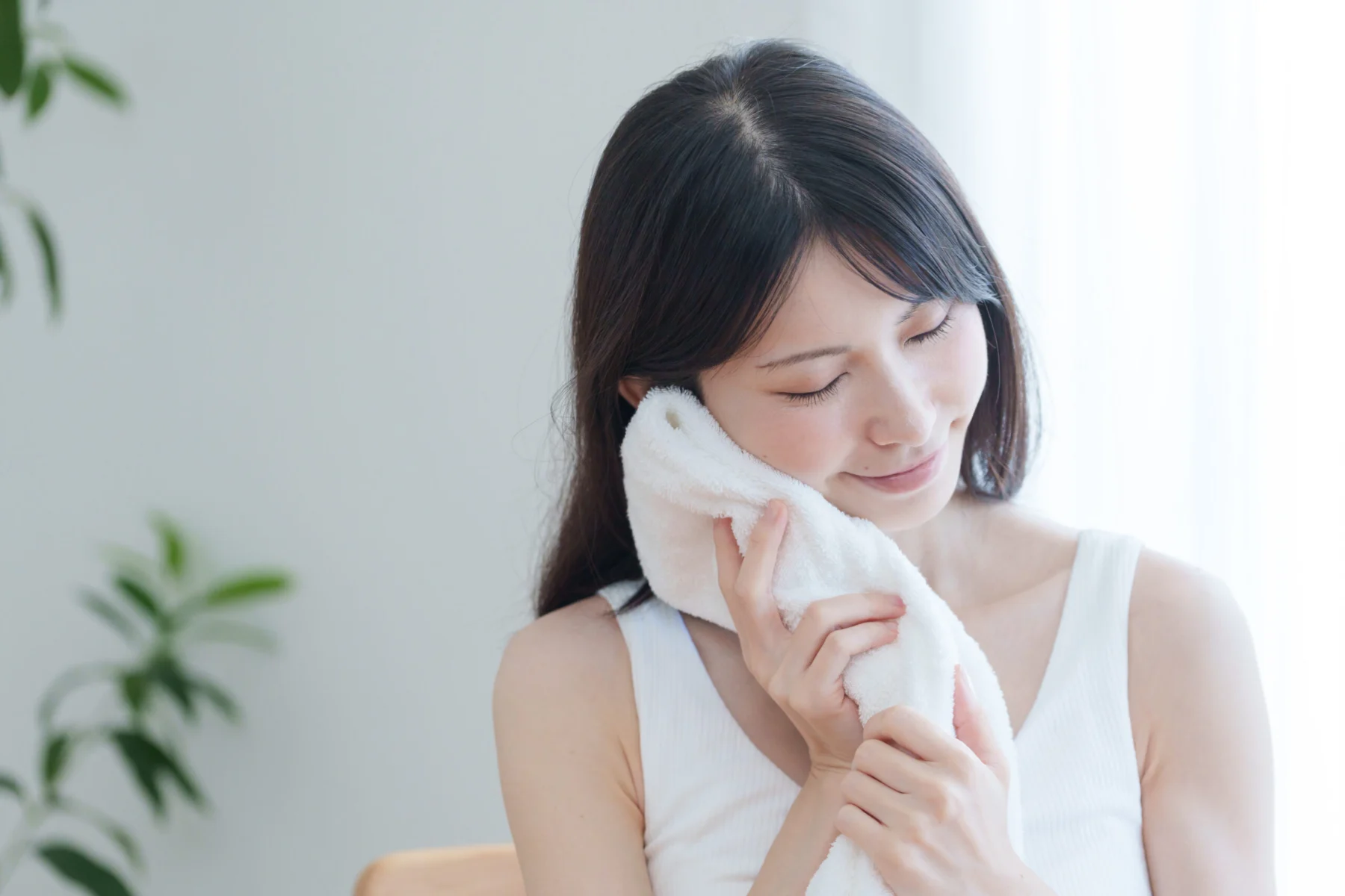 日焼け後の肌を濡れタオルでやさしく冷やして冷却ケアをする女性